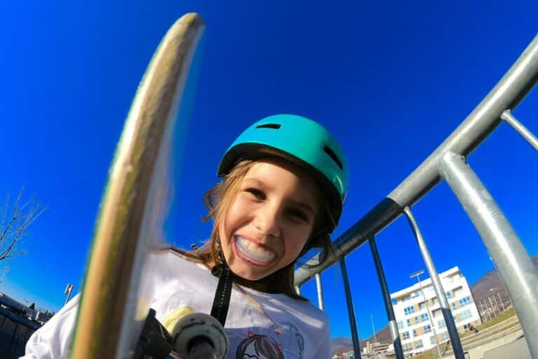 Child wearing a helmet and mouthguard while skateboarding at a skate park