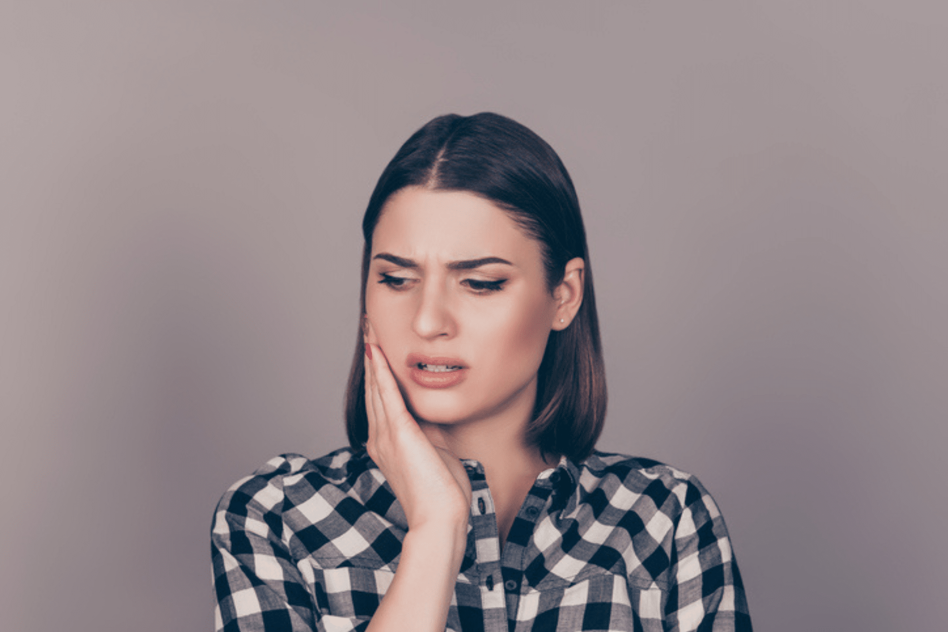 Woman holding her cheek with a concerned expression